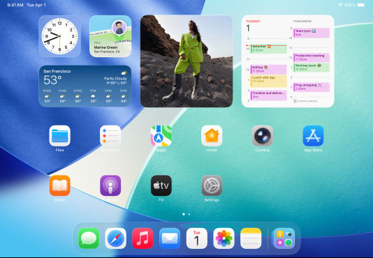 Trois modèles d’iPad, orientation paysage, avec le modèle au centre devant les deux autres, un Apple Pencil fixé de façon magnétique à son sommet, l’écran central montre l’écran d’accueil où s’affichent des icônes d’app colorées à effet Liquid Glass, l’écran de gauche montre l’app Aperçu, l’écran de droite montre l’écran d’accueil avec des fichiers qui sortent du Dock