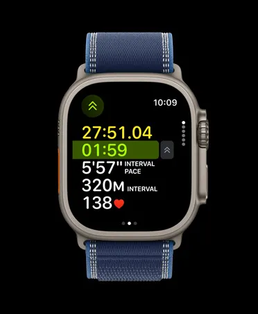 Apple Watch Ultra 3，採用原色鈦金屬錶殼，配以藍色配亮藍色越野手環；螢幕顯示户外跑步體能訓練的進階指標