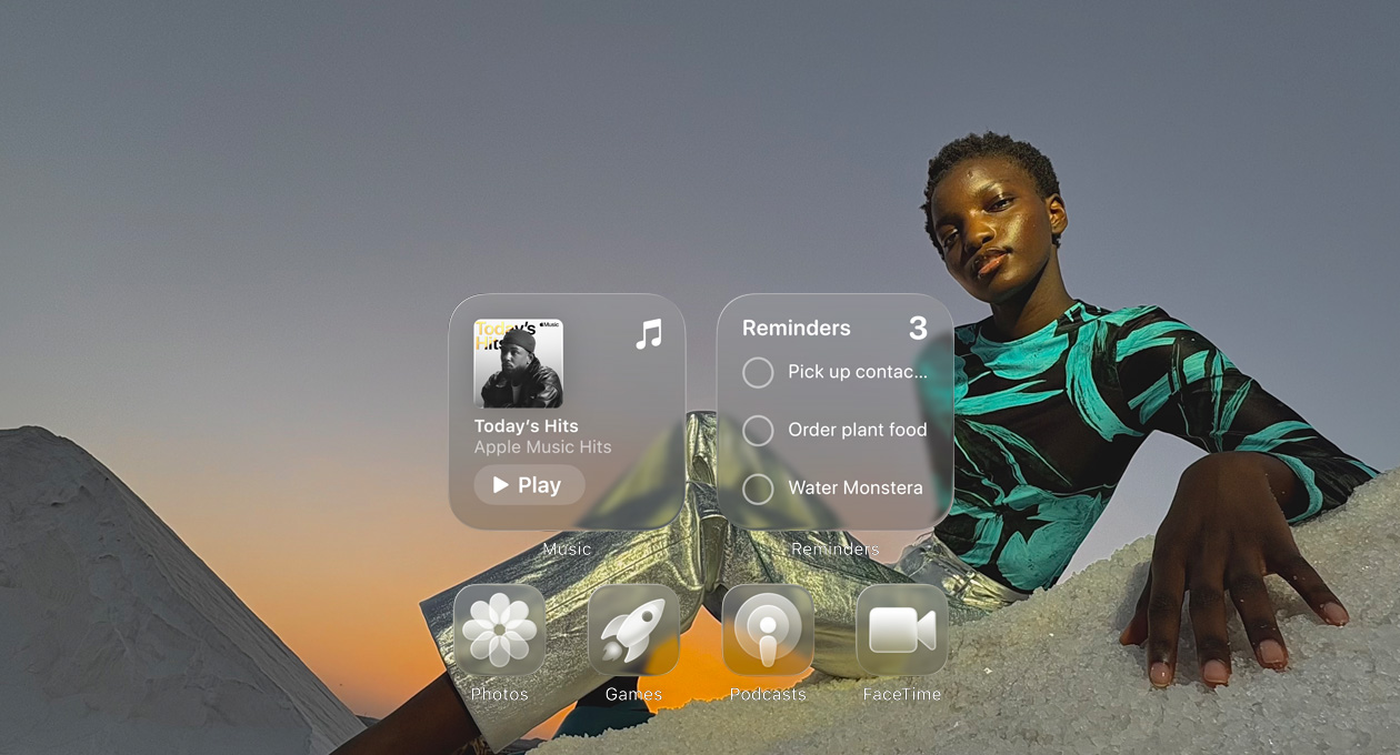 Ecrã Liquid Glass com ícones de apps transparentes, como Apple Music, Lembretes, Fotografias, Jogos, Podcasts e FaceTime, e um efeito de refração no papel de parede
